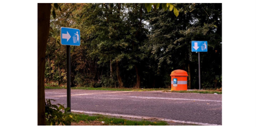 Additional signage board with an arrow pointing to the right for further clarifying the location of the rubbish bin