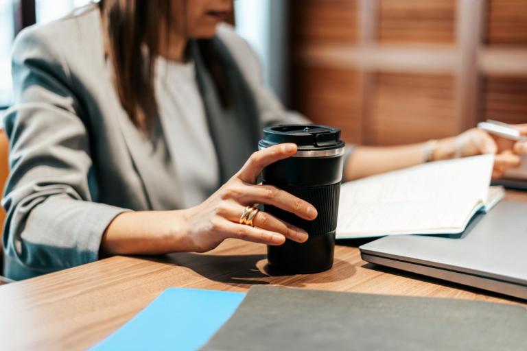 vrouw op het werk met herbruikbare koffiebeker