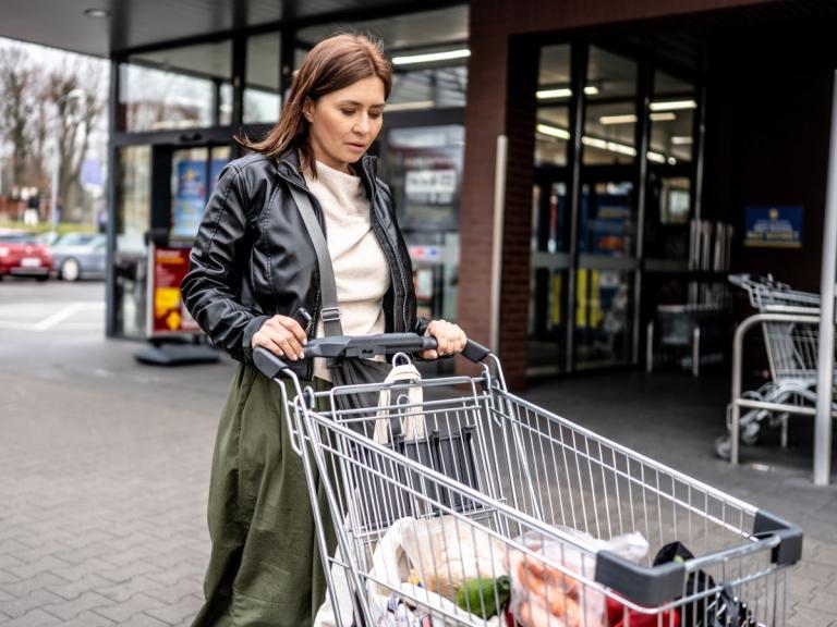 Vrouw met winkelkar bij buurtwinkel